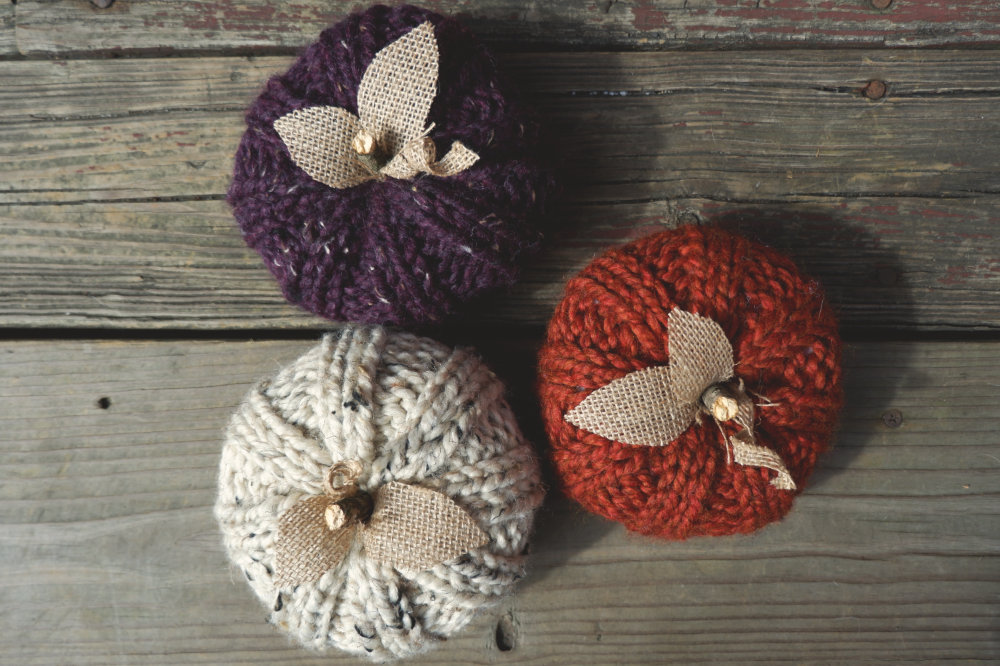 3 knit pumpkins with burlap leaves and a twig stem